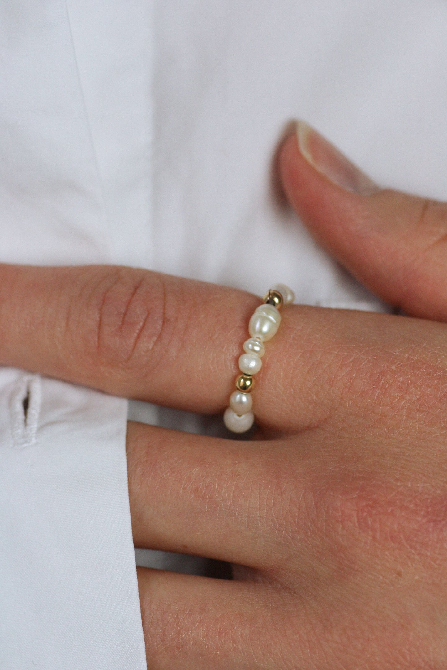 Pearl ring on a finger against a white background