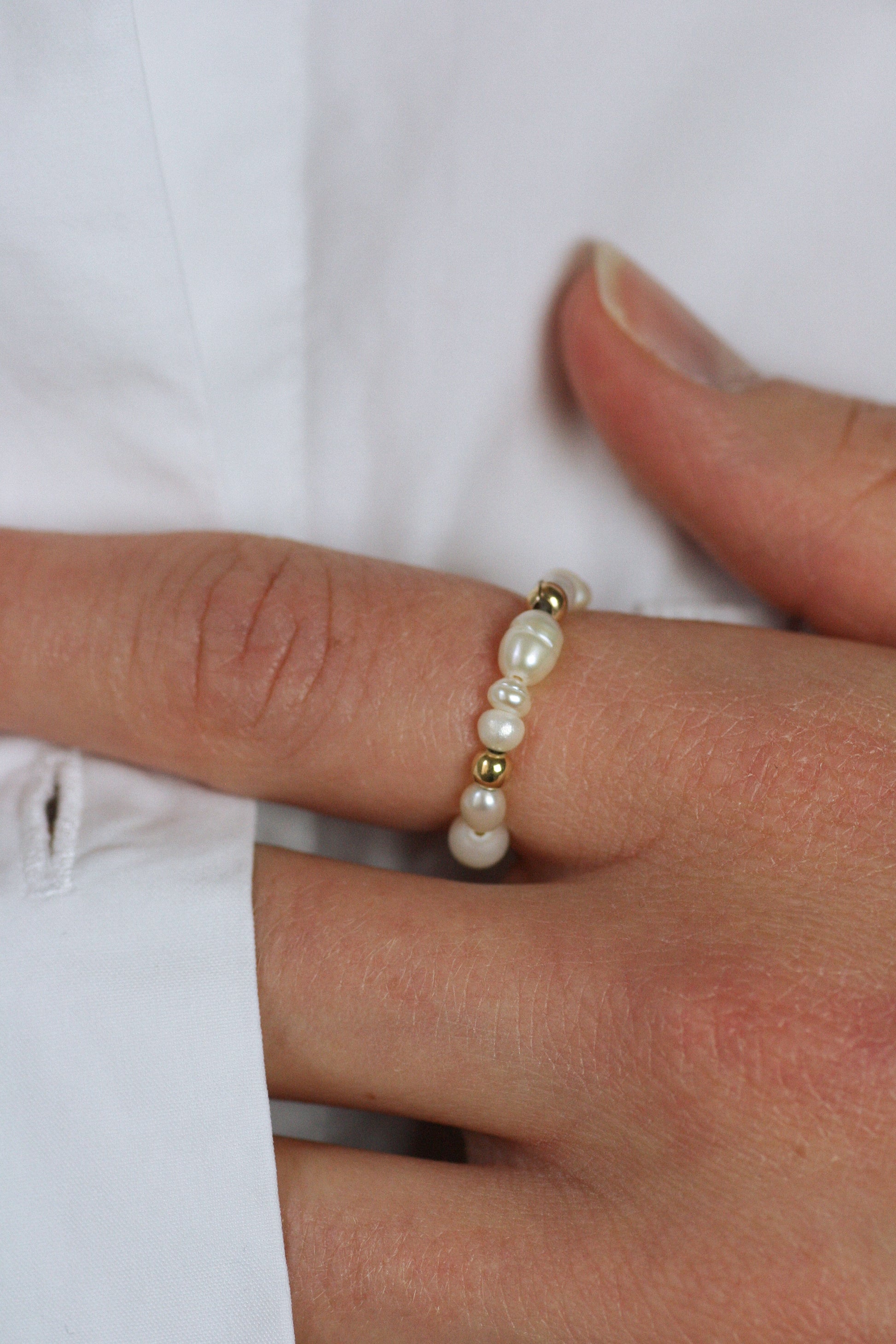 Pearl ring on a finger against a white background